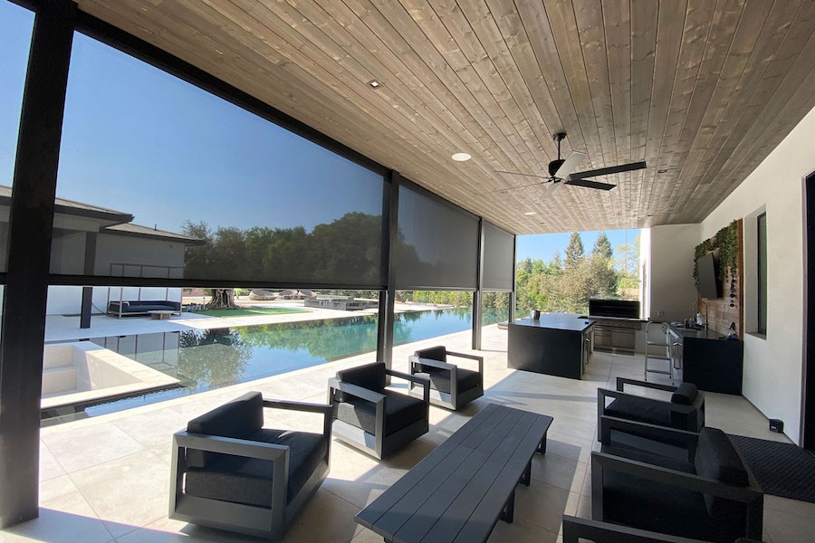 A poolside patio area with motorized shades lowered halfway. 