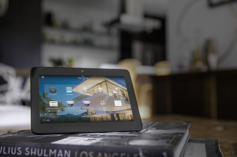 A black home automation control panel sitting on top of books in a living room. 