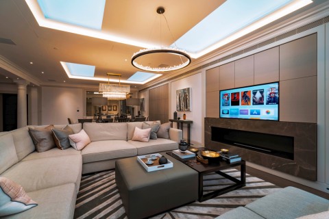 a living room with a large flat screen TV mounted over a fireplace. 