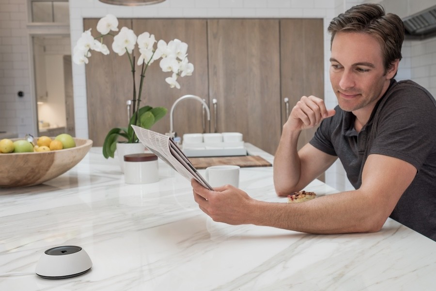 A man sitting at his kitchen island with a Josh.ai device next to him.