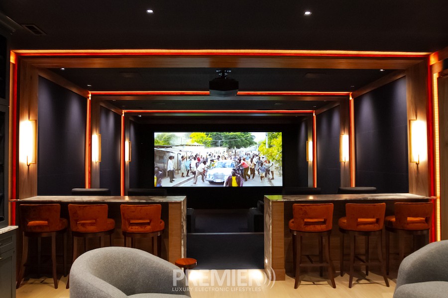 A home theater screen with bar-type seats in front of it.