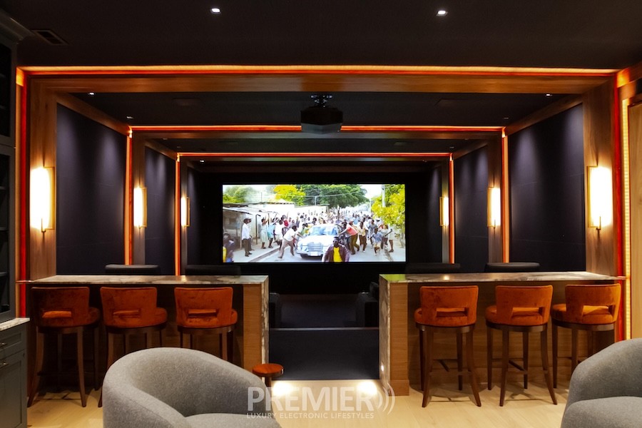 A luxury home theater with CinemaTech acoustical treatment, wood details, and wall sconces